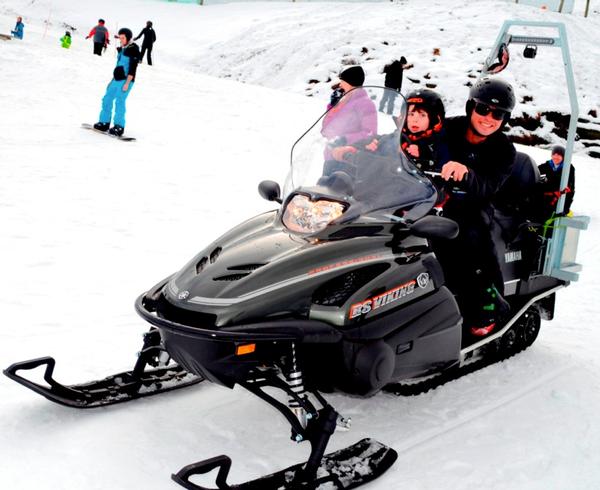 Four-year-old Katy Archer, from Auckland, who is battling Batton Disease, enjoys her first skidoo ride at Coronet Peak in the capable hands of patroller Allan Swan.  